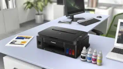 Imprimante multifonction Canon avec cartouches d'encre colorées sur un bureau moderne, idéale pour impression, numérisation et copie dans un environnement professionnel ou domestique.