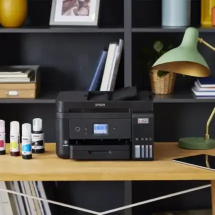 Imprimante multifonction Epson noir et blanc sur bureau avec fournitures d'impression et lampadaire vert dans un espace de bureau moderne.